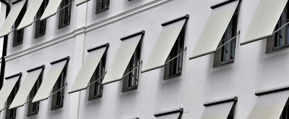 Façade d'immeuble existant équipée de stores-bannes extérieurs pour limiter les apports solaires